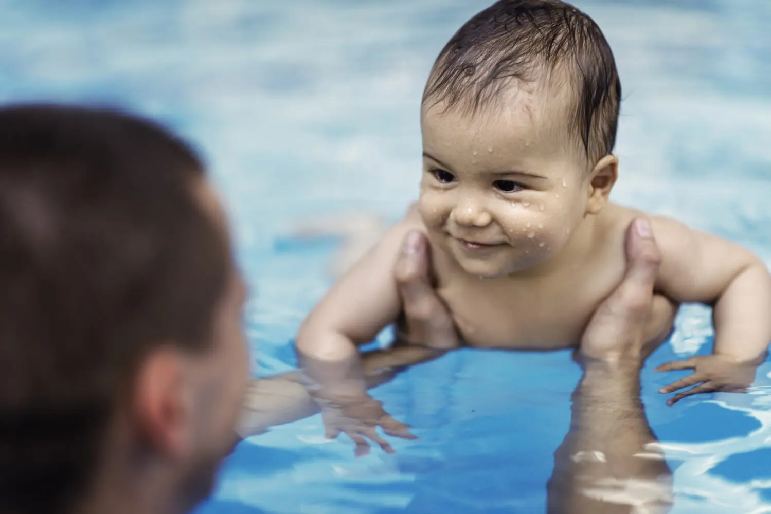 Infant in pool being held by a swimming instructor